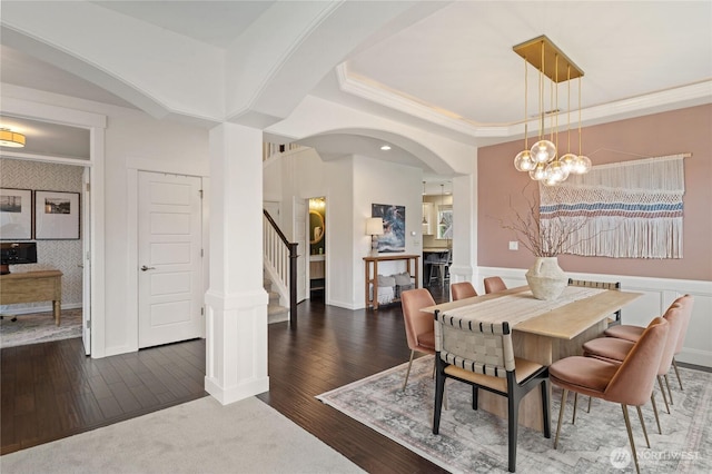 dining space featuring crown molding, a chandelier, stairs, hardwood / wood-style flooring, and arched walkways