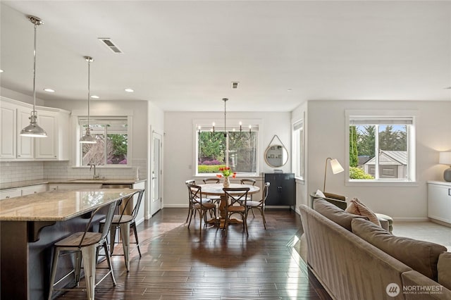 dining space with baseboards, visible vents, an inviting chandelier, recessed lighting, and dark wood-style flooring