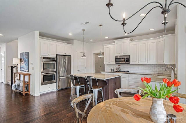 kitchen with visible vents, white cabinets, stainless steel appliances, and a sink