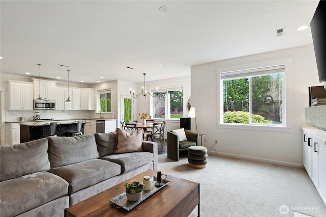 living room featuring visible vents, baseboards, light colored carpet, recessed lighting, and a notable chandelier