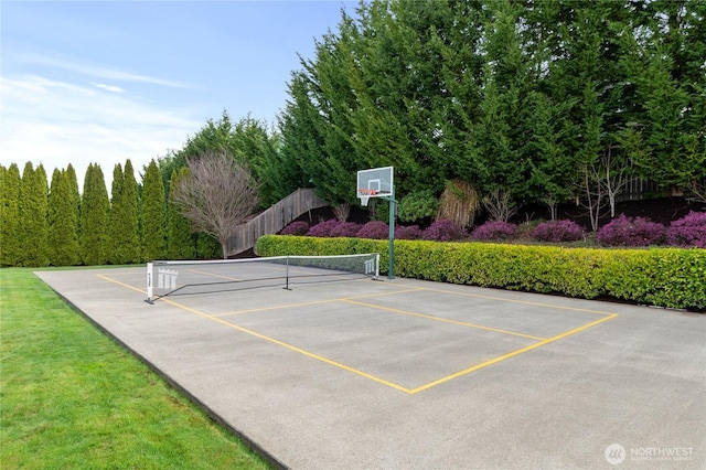 exterior space with a lawn, a tennis court, and fence