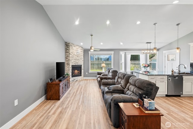 living room featuring baseboards, recessed lighting, a fireplace, and light wood-style floors