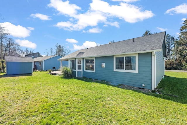 back of house featuring a yard, an outdoor structure, a shingled roof, and a storage shed