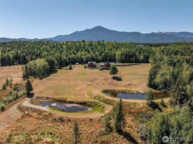 drone / aerial view with a water and mountain view and a wooded view