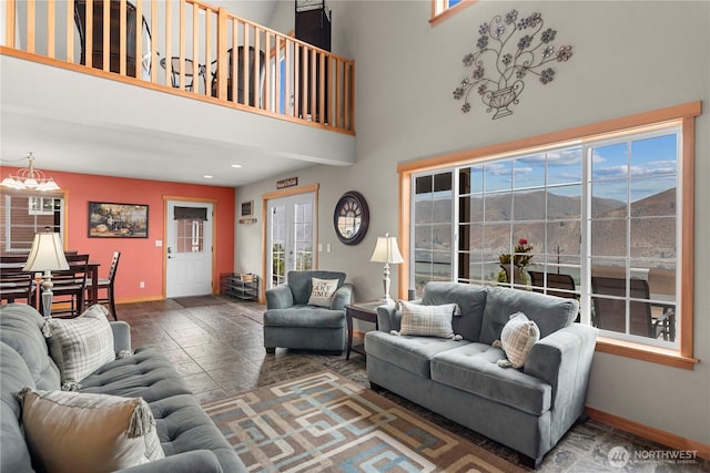 living area featuring a high ceiling, a notable chandelier, and baseboards