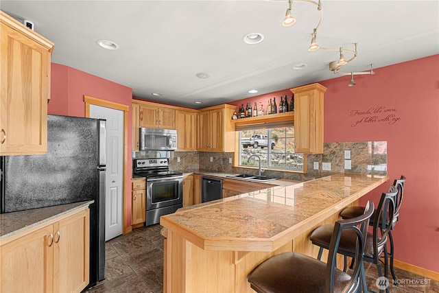 kitchen with tile countertops, a breakfast bar, a peninsula, stainless steel appliances, and a sink