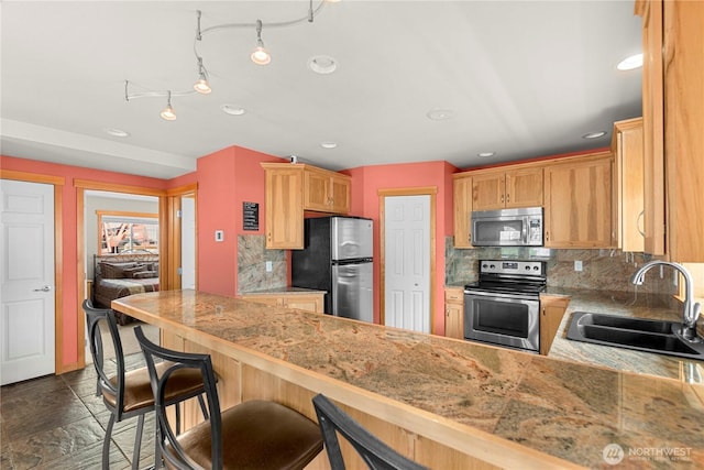 kitchen with a sink, recessed lighting, stainless steel appliances, a peninsula, and decorative backsplash