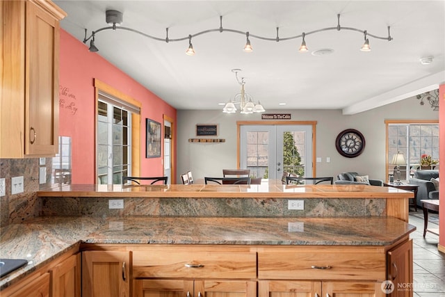 kitchen with open floor plan, french doors, black electric stovetop, a chandelier, and hanging light fixtures