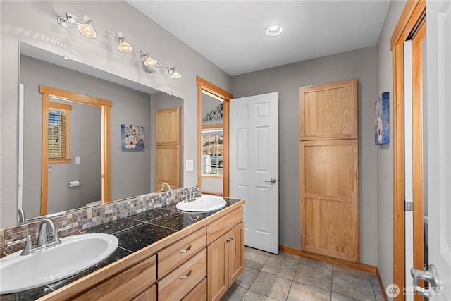 full bath featuring double vanity, tile patterned flooring, baseboards, and a sink