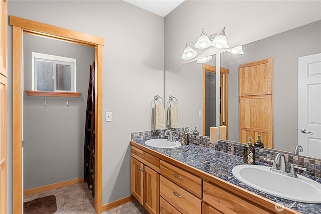 bathroom with double vanity, tile patterned floors, baseboards, and a sink