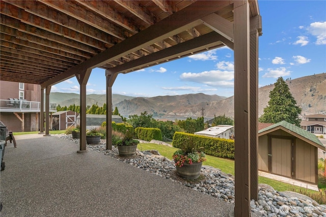 view of patio / terrace with a mountain view, a storage unit, and an outdoor structure