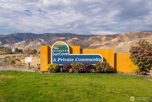 community sign with a mountain view and a lawn