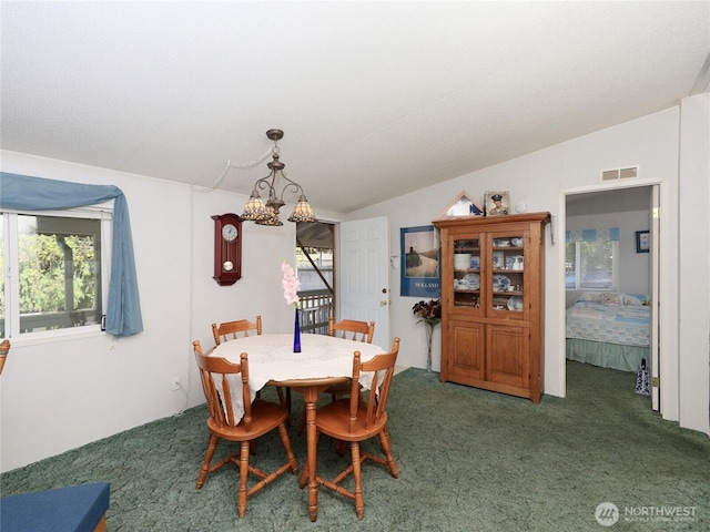 carpeted dining area featuring lofted ceiling, visible vents, plenty of natural light, and a notable chandelier