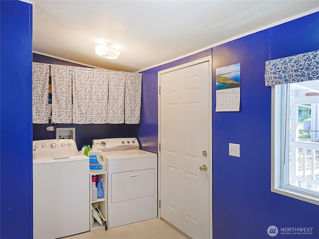 washroom with a textured ceiling, laundry area, and washing machine and clothes dryer