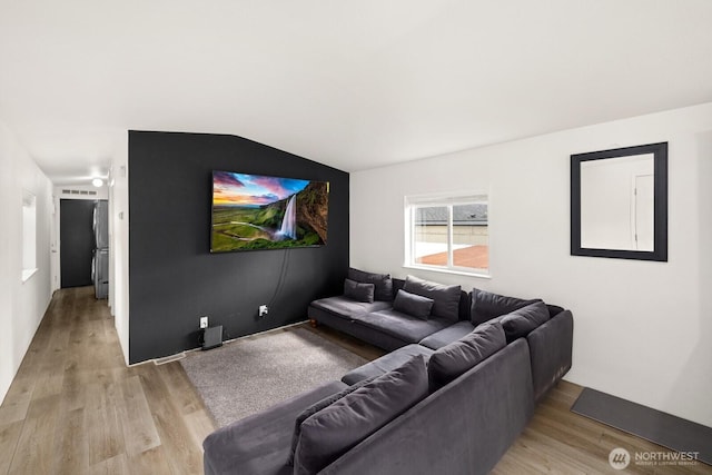 cinema with light wood-style floors and vaulted ceiling