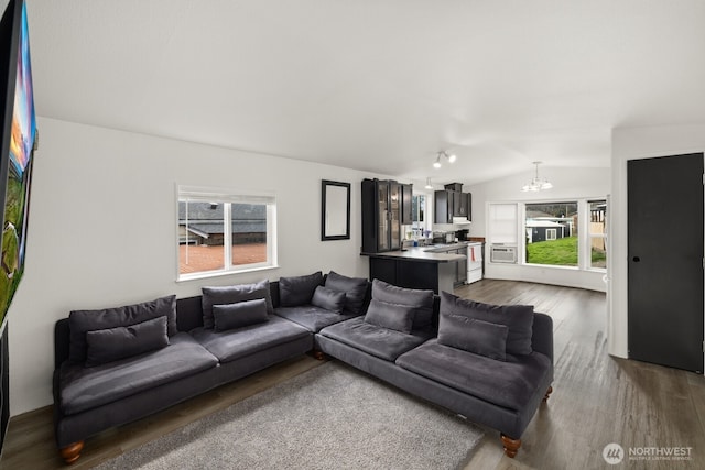 living area featuring dark wood-style floors, a chandelier, and vaulted ceiling