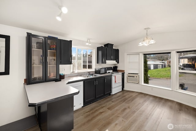 kitchen with dark cabinets, white appliances, light wood-style floors, and vaulted ceiling