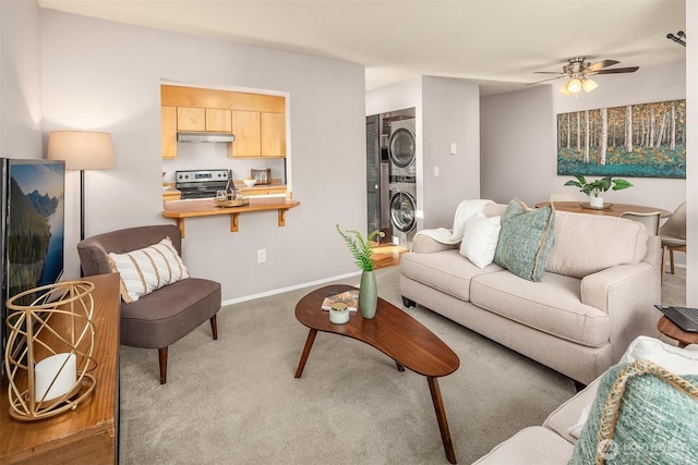 living area with stacked washer and dryer, carpet floors, a ceiling fan, and baseboards