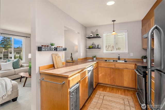 kitchen featuring wine cooler, a sink, appliances with stainless steel finishes, open shelves, and light wood finished floors