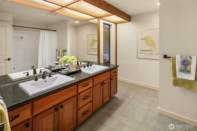 full bathroom with double vanity, baseboards, and a sink