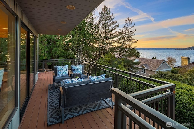 balcony at dusk with a water view and an outdoor hangout area