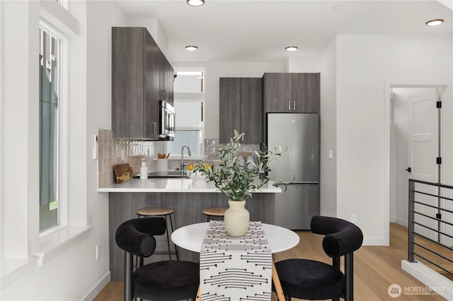 kitchen with dark brown cabinets, appliances with stainless steel finishes, a breakfast bar area, and light countertops