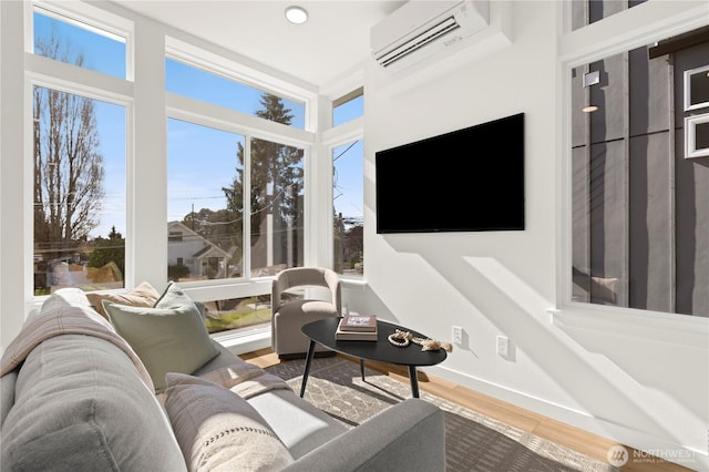 living room featuring a wall mounted AC, wood finished floors, and baseboards