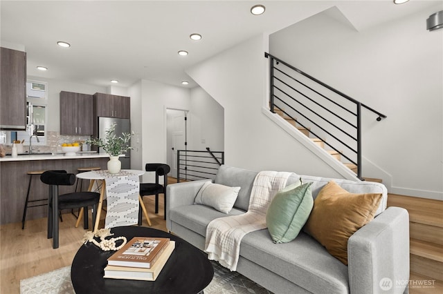 living area with stairs, light wood-type flooring, and recessed lighting