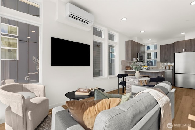 living area with recessed lighting, baseboards, wood finished floors, and a wall mounted air conditioner