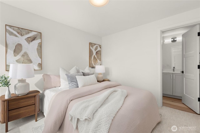 bedroom with light wood-style floors and connected bathroom