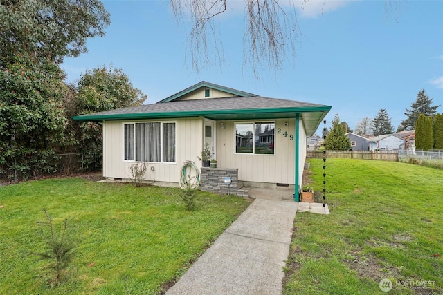 bungalow-style house with a front yard, fence, roof with shingles, and crawl space