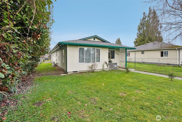 rear view of house featuring crawl space, a lawn, roof with shingles, and fence