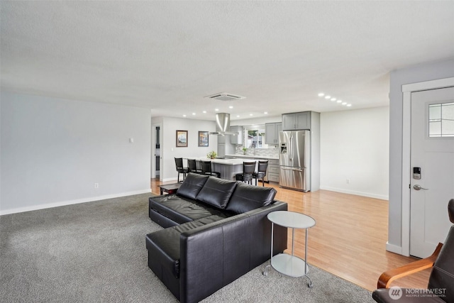 living area featuring light wood-style flooring, recessed lighting, baseboards, and visible vents