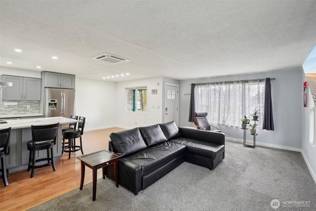 living room featuring recessed lighting, visible vents, baseboards, and a textured ceiling