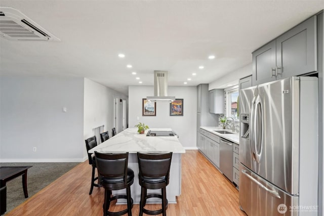 kitchen featuring a kitchen island, island exhaust hood, a sink, gray cabinetry, and stainless steel appliances