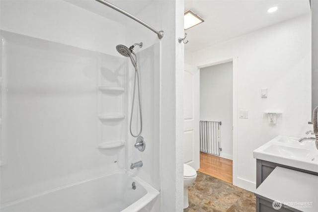 full bath featuring stone finish flooring, baseboards, shower / washtub combination, toilet, and vanity