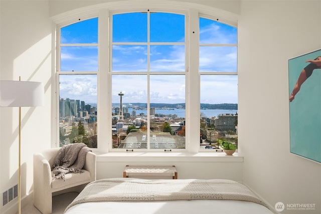 bedroom featuring visible vents, a water view, and a city view