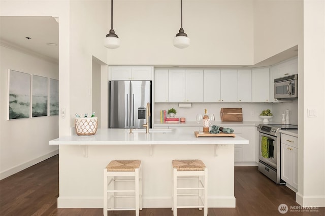 kitchen featuring a breakfast bar, light countertops, white cabinets, stainless steel appliances, and a sink