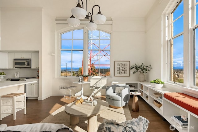 living area with dark wood finished floors, a high ceiling, crown molding, and baseboards