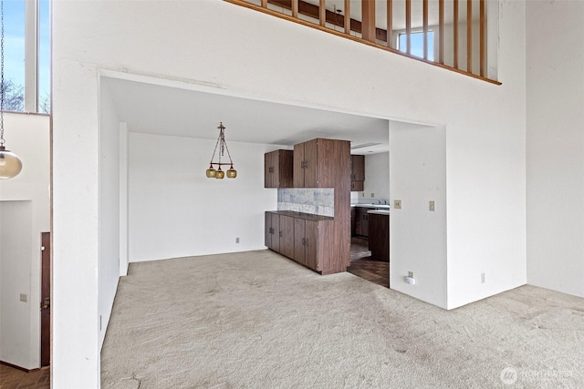 unfurnished living room featuring carpet floors and a high ceiling