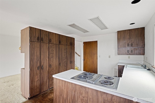 kitchen featuring stainless steel electric cooktop, light countertops, a sink, and a peninsula