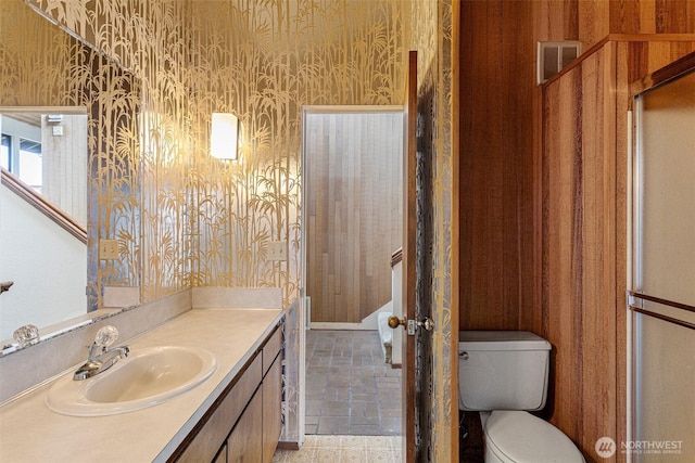 bathroom with visible vents, vanity, toilet, and wallpapered walls