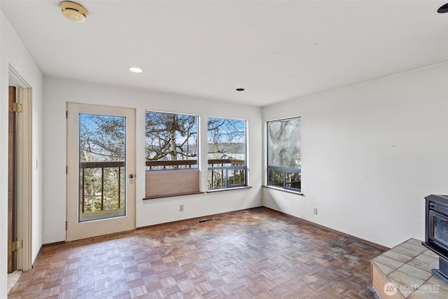 interior space with a wood stove, visible vents, baseboards, and recessed lighting