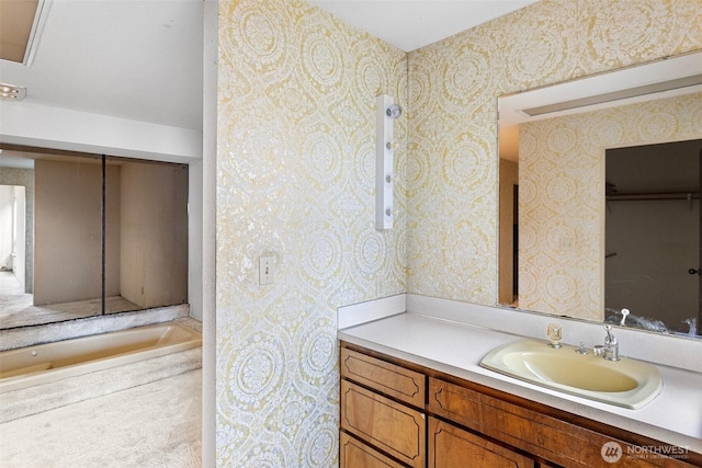 full bathroom featuring a bathing tub, vanity, and wallpapered walls