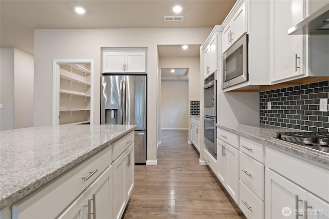 kitchen with visible vents, backsplash, under cabinet range hood, stainless steel appliances, and white cabinetry