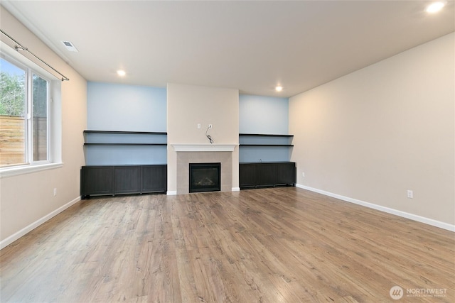 unfurnished living room featuring visible vents, baseboards, wood finished floors, and a fireplace