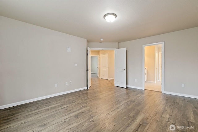 spare room featuring baseboards and wood finished floors