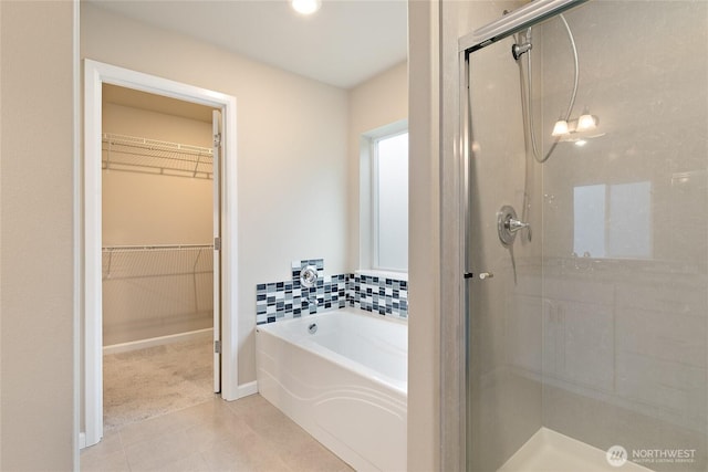 bathroom featuring a bath, tile patterned floors, a stall shower, and a spacious closet