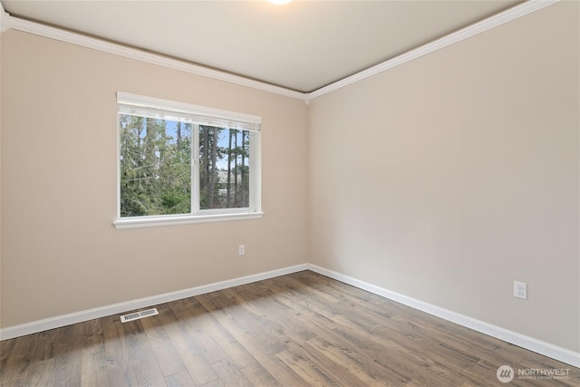 unfurnished room with visible vents, wood finished floors, baseboards, and ornamental molding