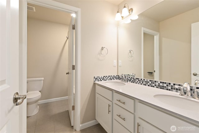 bathroom with tasteful backsplash, tile patterned flooring, toilet, and a sink